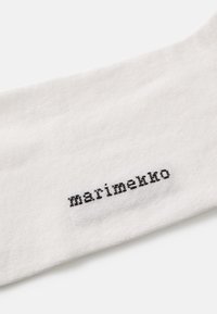 Calzino bianco in cotone con il testo ricamato in nero "marimekko" in un font semplice e moderno. Texture liscia, senza ulteriori motivi o accenti.