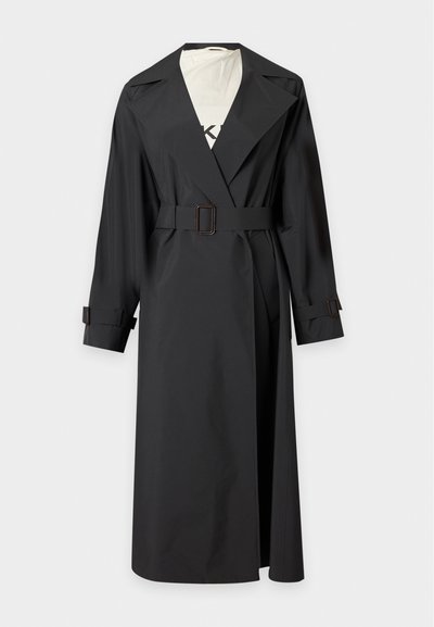 Μακρύ μαύρο trench coat με ζώνη, φαρδιές πέτους και λεπτομέρειες με αγκράφες στις μανσέτες, εμφανίζεται σε λευκό φόντο.