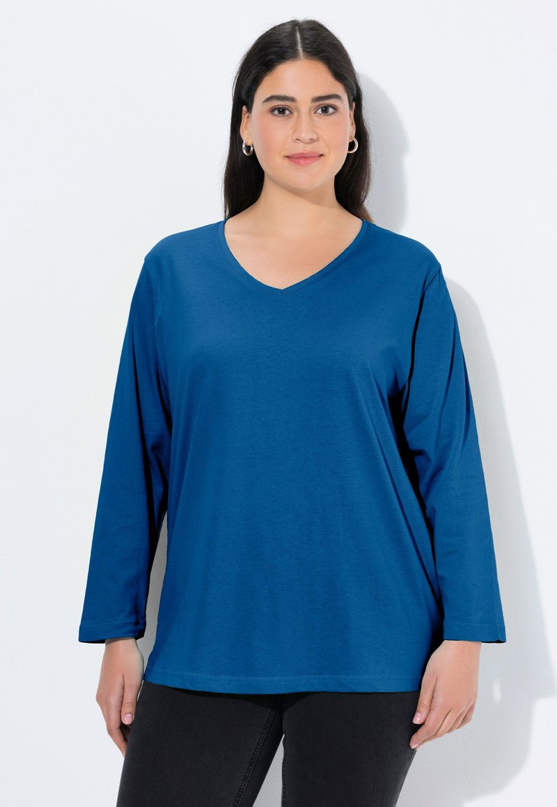 Koszula z długim rękawem i dekoltem w serek w jednolitym niebieskim kolorze, wykonana z miękkiej tkaniny o luźnym kroju, z prostym dołem i minimalnymi zdobieniami.