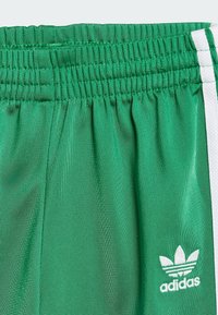 Zielone sportowe szorty z elastycznym pasem, ozdobione białymi bocznymi paskami i małym białym logo Adidas na przedniej, dolnej części.