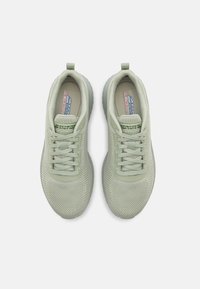 Zapatillas deportivas de color verde claro con parte superior de punto texturizado, punta redondeada, diseño de cordones y suela acolchada. Cuenta con un asa en el talón.
