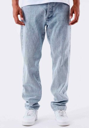 Lichtblauwe denim jeans met een relaxte pasvorm, met vervaagde details, gestikte naden en opgerolde zomen, gecombineerd met witte sneakers.