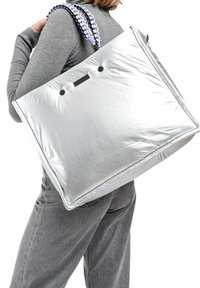 Sac fourre-tout en métal argenté avec une texture douce, présentant des poignées tressées bicolores et des accents de bouton noir. Grande forme rectangulaire.