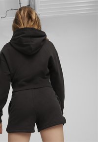 Cappotto corto nero e pantaloni corti abbinati realizzati in morbido tessuto in misto cotone, con cappuccio regolabile e tasche decorate.