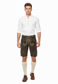 Bruna läderhosen med gul sömnad och blomsterbroderi, kombinerat med en vit långärmad skjorta, knä-långa krämfärgade strumpor och bruna skor.