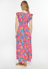 Maxi-jurk van helder roze stof met bloempatronen in blauw en oranje. Gerimpelde cap sleeves en een gelaagd ontwerp. Bruine platform sandalen.