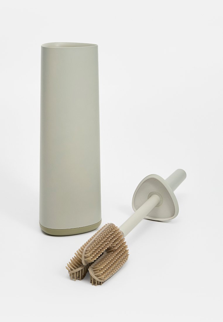 Toilettenbürsten-Set mit einem hohen, zylindrischen Halter in mattem Hellgrau. Die Bürste hat einen doppelseitigen Borstenschaft mit einem beigen Fuß und einem ergonomischen Griff.