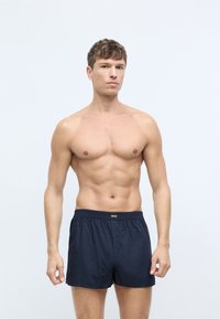 Pantaloni da mare blu navy realizzati in tessuto leggero, con vita elasticizzata decorata dal logo del marchio e un design ampio.