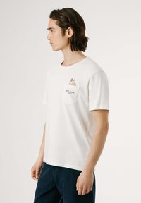 Witte katoenen t-shirt met korte mouwen, voorzien van een zak met een hondenillustratie en de tekst "Pepe Jeans London". Rechte pasvorm.