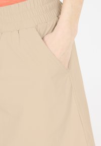 Beige shorts met eenGatherde tailleband, zijzak en een soepele structuur, die de ontspannen pasvorm en praktische ontwerp benadrukken.