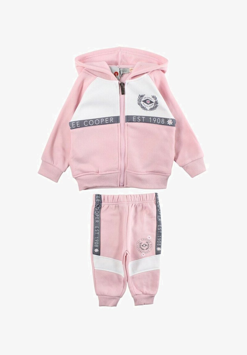 Ensemble de survêtement en coton rose comprenant un sweat à capuche zippé avec des accents blancs et un logo, accompagné d'un pantalon de survêtement assorti avec des bandes latérales.