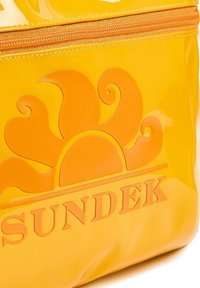 Beauty case giallo lucido con un design a rilievo a forma di sole e la parola "SUNDEK" in arancione. Presenta una chiusura zip e una superficie liscia.