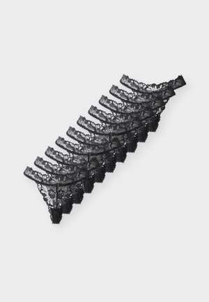 Pile de huit strings en dentelle noire pour femmes, disposés en diagonale sur un fond clair.