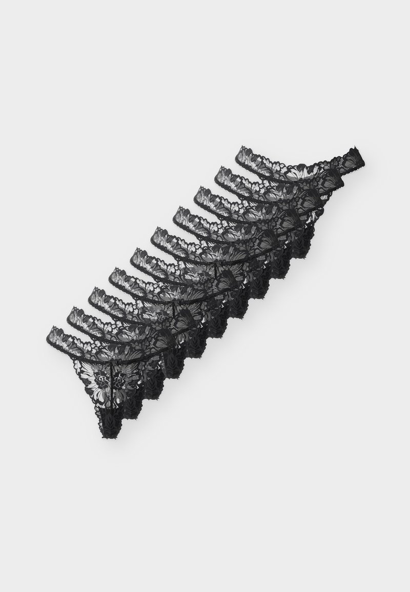 Pile de huit strings en dentelle noire pour femmes, disposés en diagonale sur un fond clair.