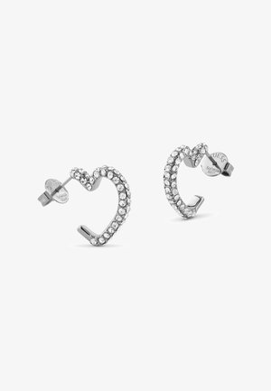 Boucles d'oreilles en forme de cœur en argent ornées de strass transparents, avec un design légèrement tordu et un fermoir à clou pour un port sécurisé.