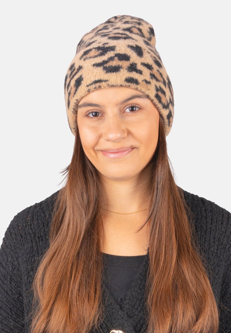 Knit beanie in beige with black leopard print, featuring a soft texture and a fitted shape, suitable for casual wear or warmth.