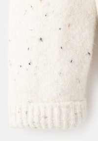 Debel kremni pulover z manšetami iz grobega pletenja, z rahlimi črnimi in zlatimi tlemi. Rebrasta tekstura ob robu dodaja vizualni interes in mehkobo.