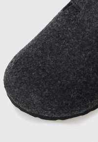 Black felt slipper featuring a rounded toe, textured surface, and a durable rubber sole with a subtle contrasting edge.