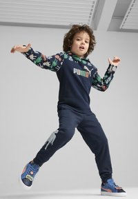 Sudadera de marina con mangas de estampado animal, logotipo de Puma, pantalones de marina a juego con un detalle gráfico y zapatillas azules con un acento divertido.