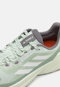 Baskets de sport vert clair avec des accents gris, tige en mesh texturé et marquage à rayures blanches. Équipées d'un système de laçage et d'une doublure intérieure rembourrée.