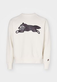 Felpa color crema con maniche raglan, caratterizzata da una grafica nera e marrone di un lupo che salta sul davanti e un piccolo logo di gelato sulla manica.