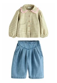 Chemise à carreaux vichy verte avec un col volanté rose et deux poches, associée à un short en denim plissé bleu.