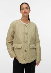 Beige quiltet jakke med rund halsudskæring, fem knapper og to forlommer. Glat tekstur med en afslappet pasform og skuldersømme.