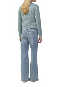 Lichtblauwe spijkerjack met een getailleerd ontwerp, knoopmanchetten en twee achterzakken, gecombineerd met lichtgewassen flared jeans.