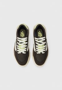 Brown canvas sneakers with white lace-up design, light green accents, and a gum sole. Features a textured surface and logo detail on the tongue.