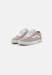 Grå semsket sneakers med hvite lisser, rund tå, gummisåle, og en svart aksentlinje. Har en logo på tungen og siden.