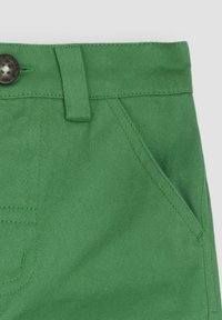 Zelené bavlnené šortky s hladkou textúrou, obsahujúce zapínanie na gombík, pútka na opasok a bočné vrecká. Šitie je viditeľné v zodpovedajúcej farbe.