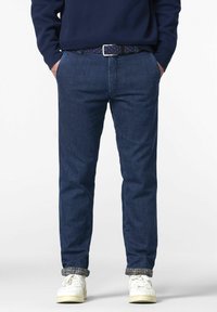 Pantalon en denim bleu à coupe droite, orné d'une ceinture tissée bleu marine. Les poignets retroussés révèlent une doublure à carreaux. Associe avec des baskets blanches.