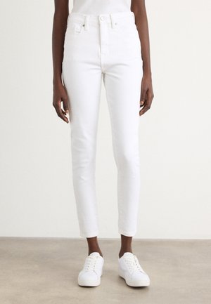 Witte skinny jeans met hoge taille en vijf-pocketontwerp. Zachte textuur, aansluitende pasvorm en enkel lengte. Gecombineerd met witte sneakers.