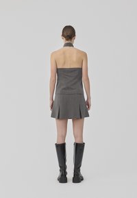 Hallide mustriga hall halter-särk, mis on sobiva bodice'iga ja volditud mini-seelikuga, millele on lisatud kõrged mustad nahksaapad. Minimalistlik disain ja tekstuur.