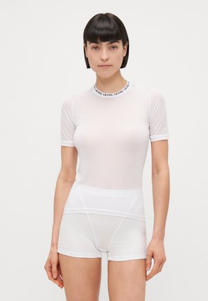 Haut à manches courtes en mesh blanc avec un col rond comportant le texte "LE COL". Assorti avec un short texturé blanc. Tissu doux.