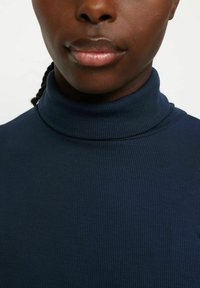 Navy blue ribbed turtleneck sweater with textured fabric. Close fit around the neck, smooth finish, and subtle stitching details.
