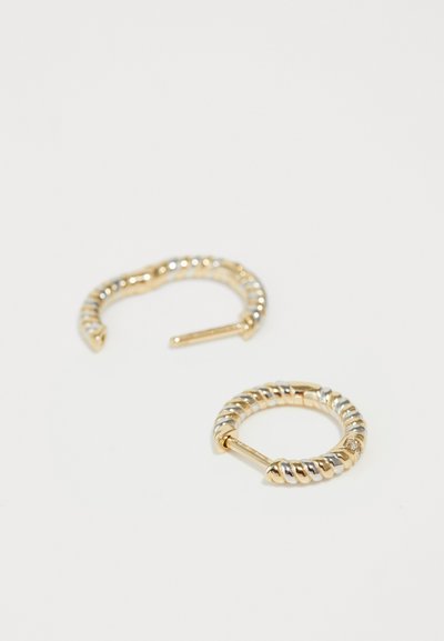 Zlaté kruhové náušnice s prekrúteným dizajnom a hladkým povrchom a lesklou textúrou. Obsahujú bezpečné otvorené zapínanie pre jednoduché nosenie.