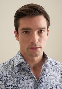 Heren blauw bloemenoverhemd met een gedetailleerd patroon van donkerblauwe bloemen, gestructureerde kraag en een zachte stofstructuur.