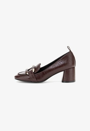 Scarpa con tacco alto in pelle marrone con punta arrotondata, dotata di una fascetta anteriore e di un accento dorato, e un tacco a blocco. Finitura texturizzata, suola liscia.