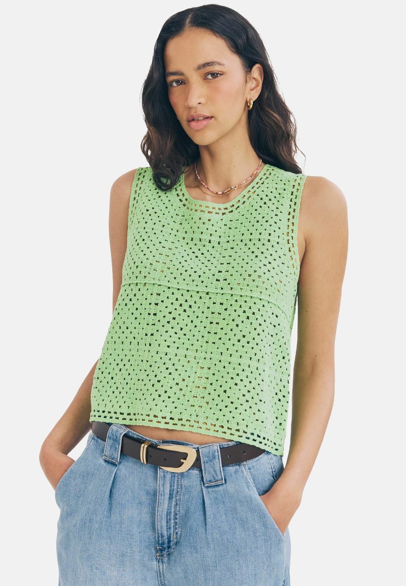 Groen gebreid tanktop met een losse pasvorm, voorzien van een geperforeerd patroon en een ronde halslijn, gecombineerd met hoge blauwe denim shorts.