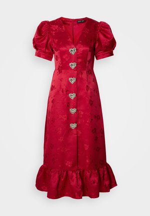 Rochie roșie din satin, cu mâneci bufante, tiv ondulat și model floral embosat. Prezintă cinci butoane argintii în formă de inimă pe față.