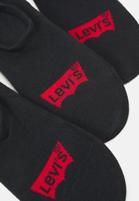 Svarta ankelsockor med en röd vävd Levi's-logotyp på sidan, slät textur och klassisk design som passar för avslappnad användning.