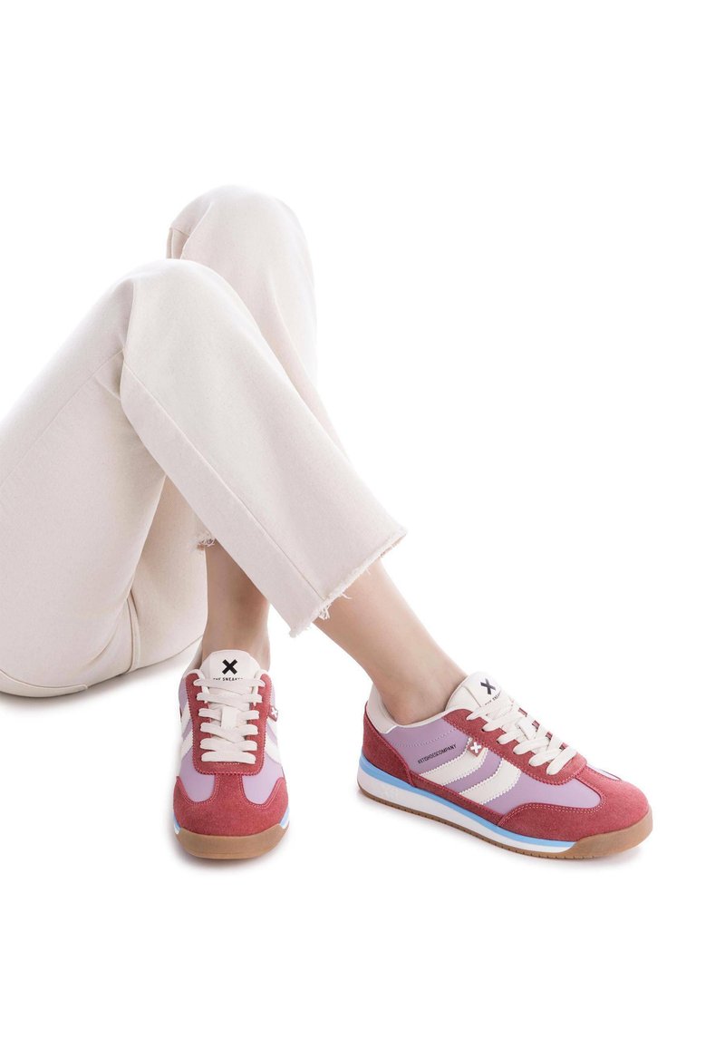 Zapatillas deportivas en rosa, morado y blanco. Materiales de ante y malla. Presentan rayas blancas, cordones redondos y suelas de goma texturizadas.