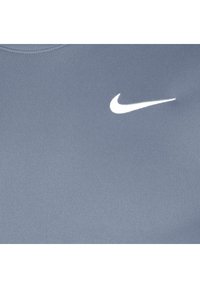 Blå atletisk skjorte lavet af glat stof, med et hvidt Nike-logo på venstre bryst. Enkel design med rund halsudskæring.