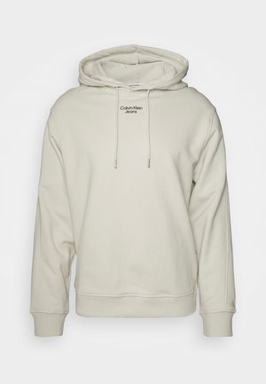Cremeweißer Calvin Klein Jeans Hoodie mit Kordelzug, gerippten Bündchen und Saum sowie Logotext mittig auf der Brust.