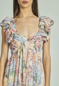 Blumenkleid mit Rüschensäulen, einem V-Ausschnitt und fließendem Stoff in sanften Farben, darunter Rosa, Lila und Grüntöne.