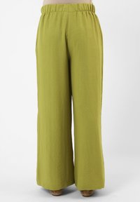 Pantalones de pierna ancha en un tono verde oliva claro, con una cintura elástica y una tela texturizada y arrugada. Sin bolsillos visibles.