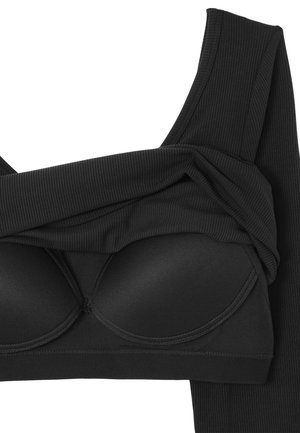 Soutien-gorge en tissu noir à rayures avec des coques rembourrées et de larges bretelles, présenté plié sur un fond blanc.