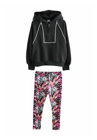 Svart zip-up hoodie med vita detaljer och känguruficka, kombinerad med färgglada, mönstrade tights i rosa, lila och svart. Material av bomullsblandning.