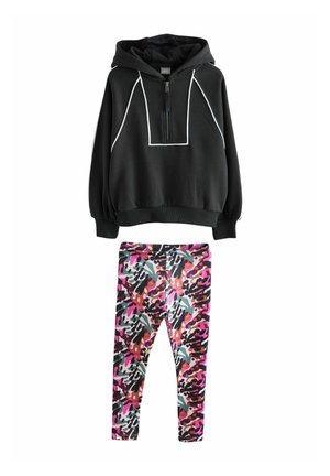 Hoodie zippé noir avec des accents blancs et une poche kangourou, associé à des leggings colorés et à motifs en rose, violet et noir. Matériel en mélange de coton.